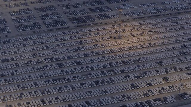 Top down aerial view of thousands of new cars parked in rows at port storage yard