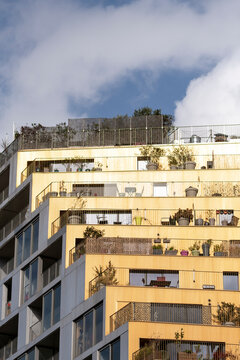 Warm balconies line a Paris Rive Gauche apartment facade, linking modern residential architecture with urban housing detail above the street