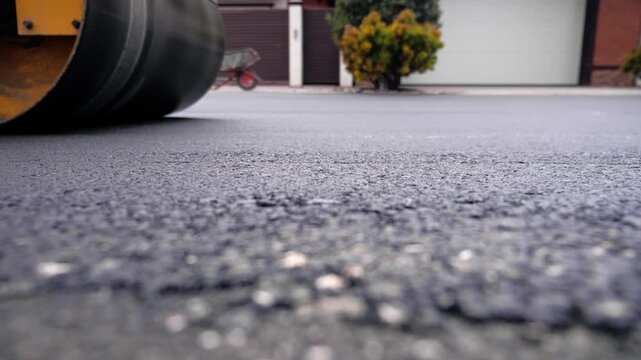 Road Roller Moving Over Fresh Asphalt Surface During Road Construction