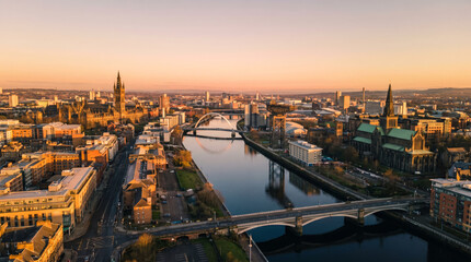 Obraz premium Panoramic aerial view of Glasgow city skyline at sunset with River Clyde and bridges.
