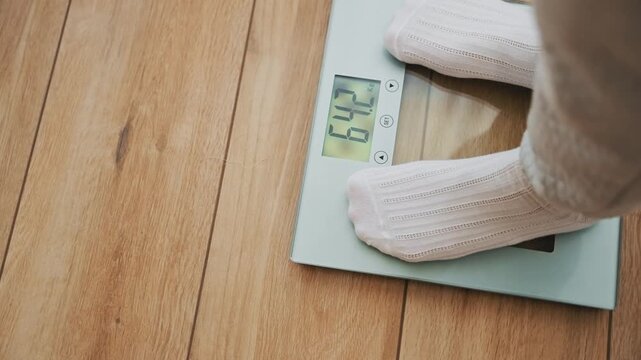 Closeup person legs bare feet stepping onto weighing scale at home. Healthy lifestyle weight awareness concept. man weight lose standing on scales measure weight. Fitness diet BMI teen male slimming