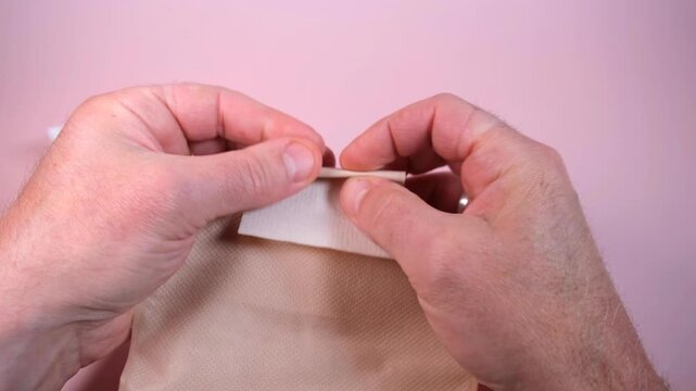 Hand folding velcro stoma pouch closure with precise motion on a paper surface for medical care.