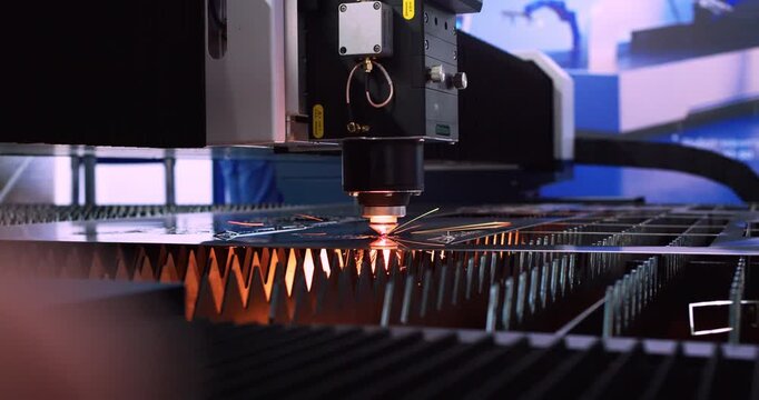 Close-up video of a high-precision industrial machine employing a laser beam to process a metal piece.