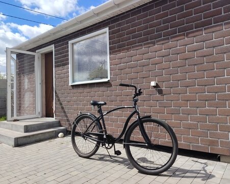 BREST, BELARUS - MAY 10, 2026: Black Schwinn cruiser bicycle parked on a paved patio outside a building under a blue sky
