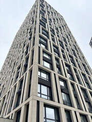 Obraz premium Modern residential building facade with rhythmic balcony design. Contemporary brick architecture and glass windows pattern.