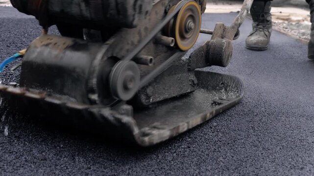 Worker Compacting Fresh Asphalt With Vibratory Plate Compactor