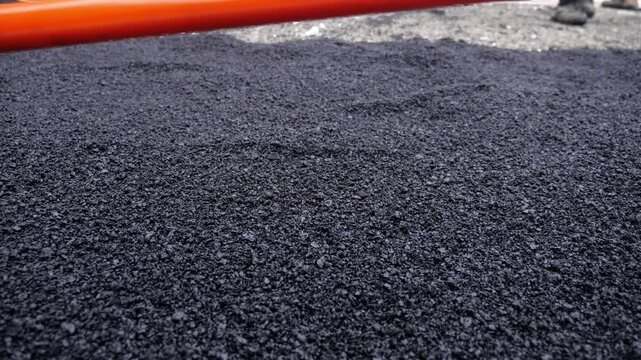 Worker Leveling Fresh Loose Asphalt by Hand During Road Paving