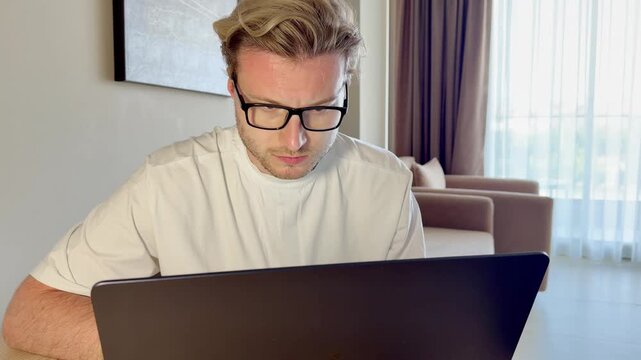 A young man works on a laptop from home