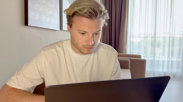 A young man works on a laptop from home