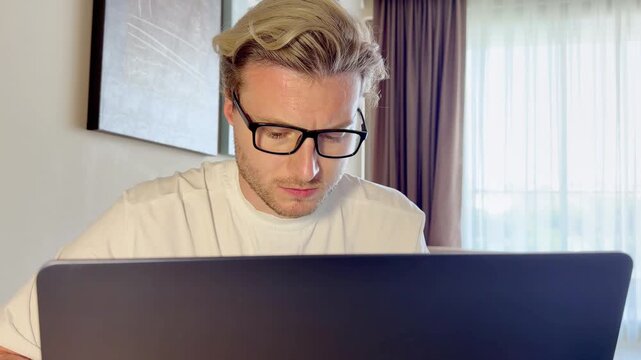A young man works on a laptop from home
