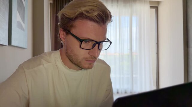 A young man works on a laptop from home