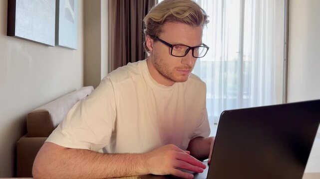 A young man works on a laptop from home