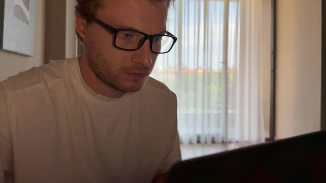 A young man works on a laptop from home