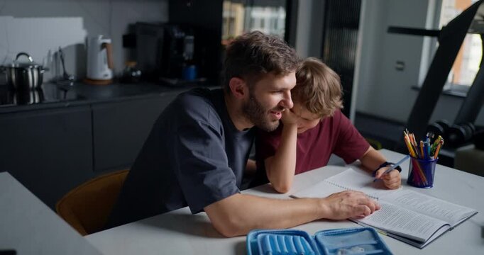 Caring Father Gently Consoles His Boy During Schoolwork At Kitchen Table With Comforting Words