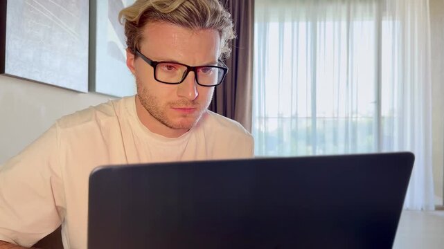 A young man works on a laptop from home