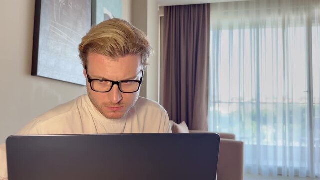 A young man works on a laptop from home