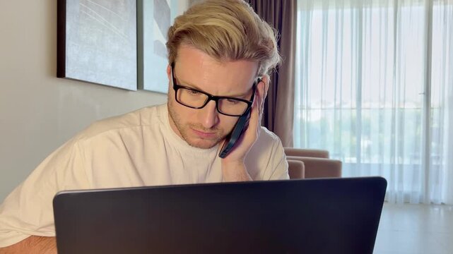 A young man works on a laptop from home
