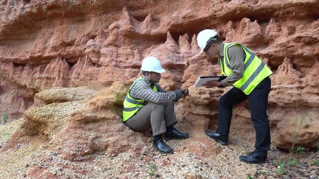 Two geologists analyzing soil and rock formations at a mining excavation site. They are conducting geological surveys and evaluating mineral resources for industrial project planning.