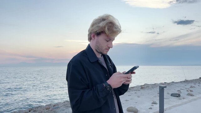 young man walking along the promenade and taking pictures.uses a smartphone