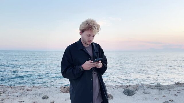 young man walking along the promenade and taking pictures.uses a smartphone