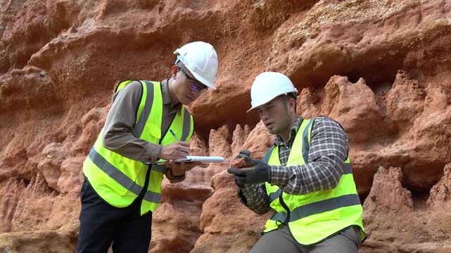 Two geologists analyzing soil and rock formations at a mining excavation site. They are conducting geological surveys and evaluating mineral resources for industrial project planning.