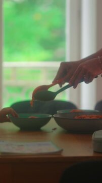 Close up of spaghetti being served onto plate during family dinner capturing nourishment, home cooking and authentic everyday mealtime routine