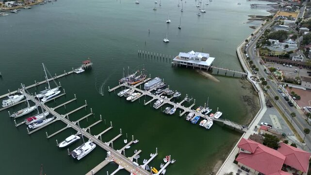 Aerial view of boats docked at a marina alongside a red-roofed building and mini-golf course in St. Augustine, Florida, United States.