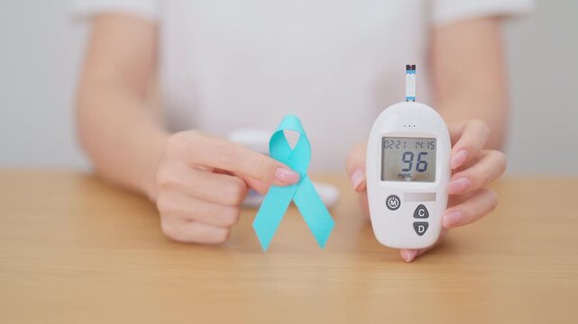 Hand show Blue Ribbon and digital blood glucose meter with lancet pen. high blood sugar level, November World Diabetes Day, Awareness month, Glycemia,, Hyperglycemia and insulin testing and checking