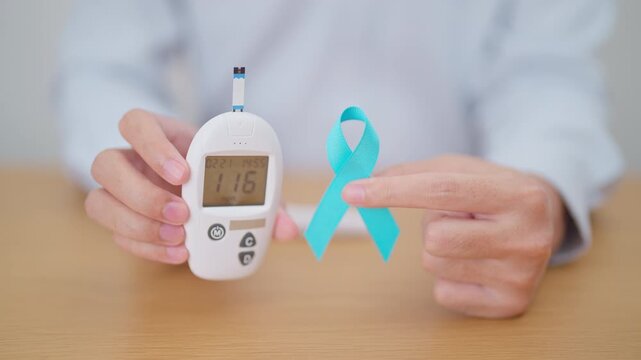 Hand show Blue Ribbon and digital blood glucose meter with lancet pen. high blood sugar level, November World Diabetes Day, Awareness month, Glycemia,, Hyperglycemia and insulin testing and checking