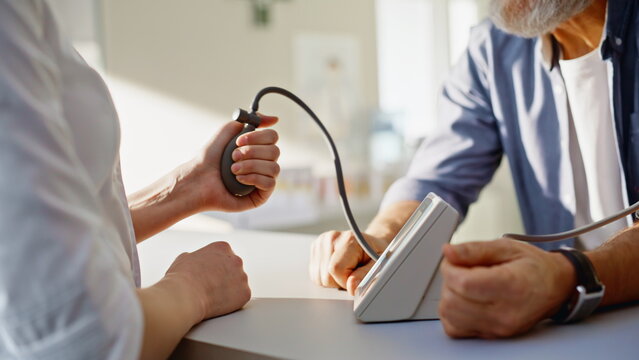 Doctor hands measuring pressure of elderly male patient in pharmacy closeup