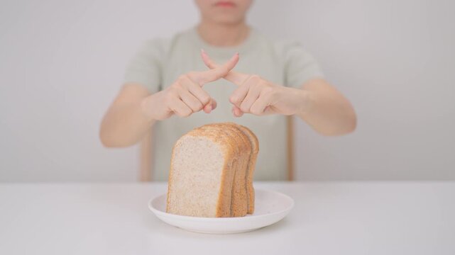 Unhappy woman showing Rejecting gesture and refusing to eat bread. concept of gluten intolerance, gluten sensitivity, carb loading concerns, or a disliking for unhealthy dietary habits