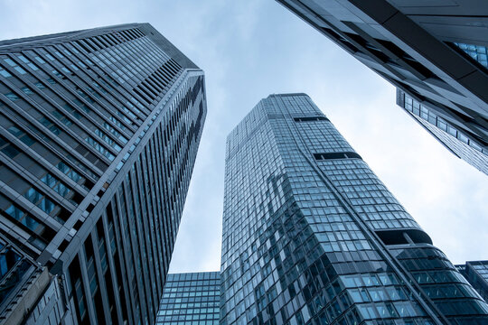 Glass skyscrapers pull the eye from a low angle in Frankfurt Germany, compressing office towers and skyline depth across the financial district