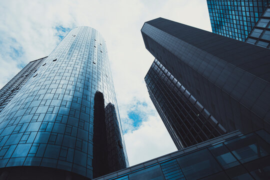 Clouds reflect across curved glass towers and facades in Frankfurt Germany, giving financial district architecture a strong upward perspective