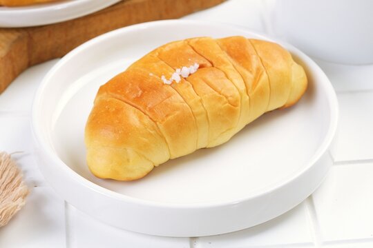 Salt bread, also known as shio pan in Japan and sogeum ppang in Korea, is a popular buttery roll with a crispy salted crust and soft airy interior, perfect for bakery and breakfast concepts.