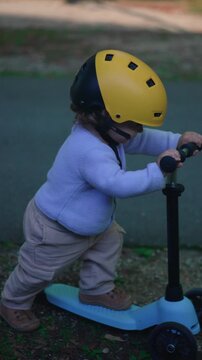 Toddler child riding scooter in park path learning balance independence outdoors concept of growth exploration and early development