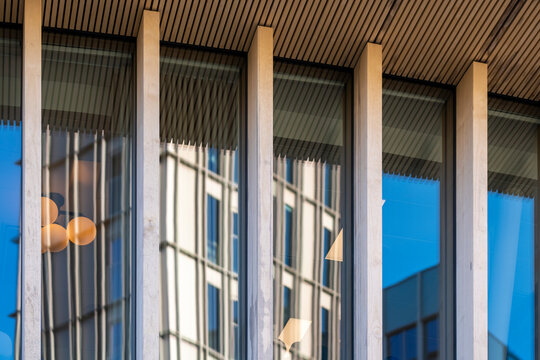 Warm light crosses windows behind a glass facade as reflections from office buildings shape abstract corporate architecture patterns