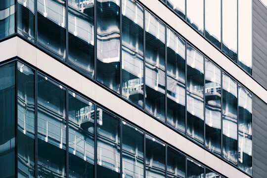 Sharp reflections run along a glass facade as office buildings repeat through windows and corporate architecture patterns become abstract geometry