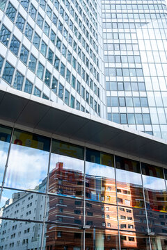 Layered office buildings show reflections through a glass facade above lower windows, connecting corporate architecture patterns with an abstract urban scene
