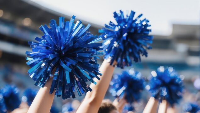 Cheerleaders raising blue pom-poms in a stadium, cheering in sunlight
