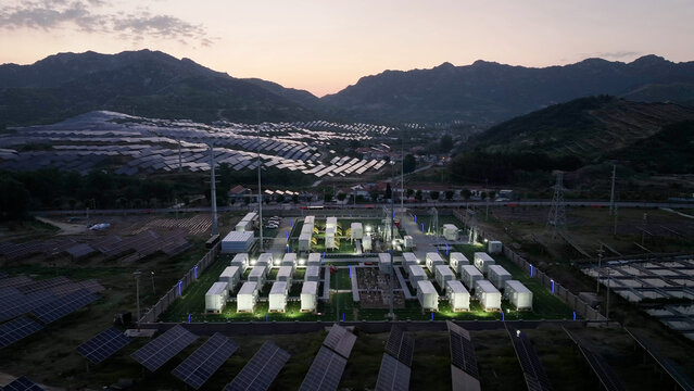 Mountainous photovoltaic power station with energy storage battery arrays illuminated at dusk