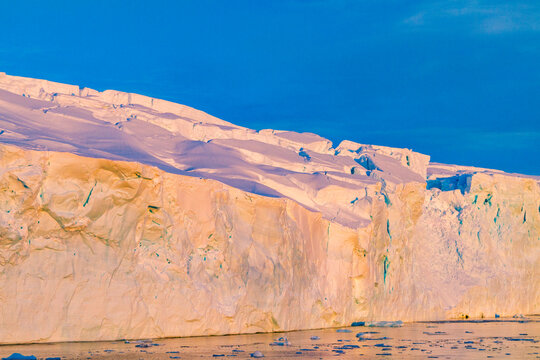 Sunset glow on icy cliffs near Stonington Island in Antarctica's Southern Ocean during late afternoon