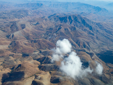 Charter flight over dry landscapes in Madagascar with clouds and hills visible below during the journey from Isalo National Airport to Antanavarino