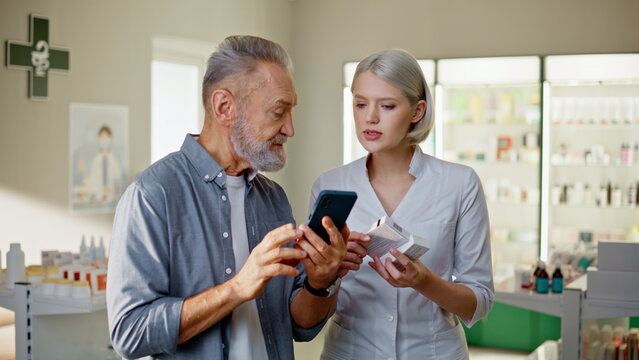 Pharmacy girl advising man prescription closeup. Patient showing smartphone