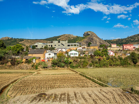 Scenery along highway N2 from Antanavarino to Andasibe in Madagascar features homes and fields under blue sky
