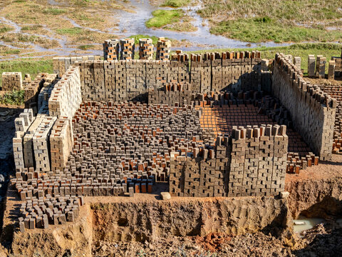 Workers shape fresh bricks from mud along highway N2 in Madagascar, contributing to local construction efforts and labor economy