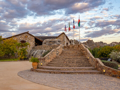 Sandstone formations surround hotel entrance in Isalo Massif, Madagascar, with flags and path leading up to the building