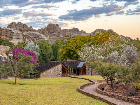 Sandstone formations provide backdrop for Relais de la Reine Hotel in Madagascar during sunset with lush vegetation around