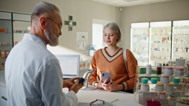 Pharmacy visitor paying smartphone buying medicine closeup. Seller packing pills