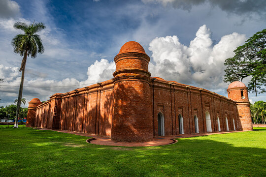 Sixty Dome Mosque in Bhagerat features red brick architecture under a cloudy sky in Bangladesh