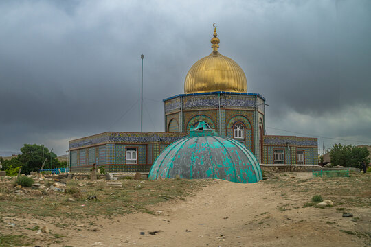 Mauolseum of Hakim Sanai stands in Ghazni, Afghanistan with a golden dome under a cloudy sky
